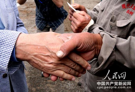 韓國議員黃震夏在合影結束后遞增農民名片，並緊緊握住白縣農民的手。(崔小粟攝)