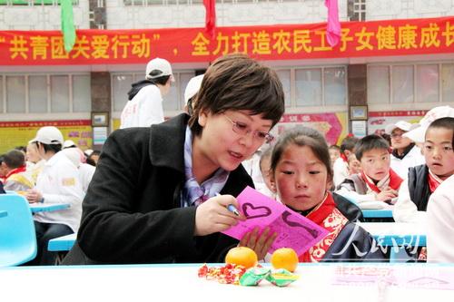 申紅興作為普通志愿者和農民工子女簽訂愛心結對卡