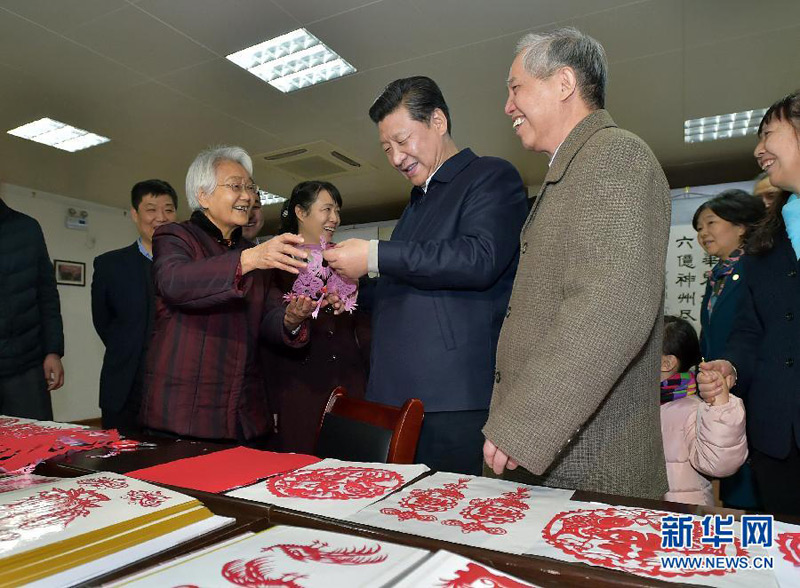 這是15日上午，習近平在西安市雁塔區電子城街道二〇五所社區服務中心欣賞社區老人的剪紙作品。 新華社記者 李濤 攝