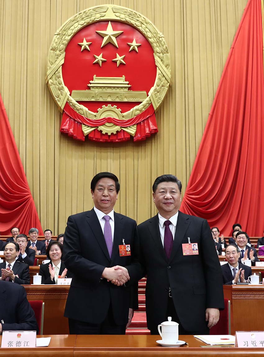 3月17日，十三屆全國人大一次會議在北京人民大會堂舉行第五次全體會議。習近平當選中華人民共和國主席、中華人民共和國中央軍事委員會主席。這是習近平在主席臺上同新當選的全國人大常委會委員長栗戰書握手。新華社記者 鞠鵬 攝