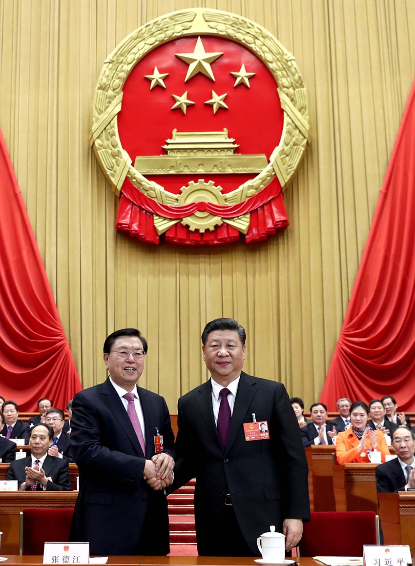 3月17日，十三屆全國人大一次會議在北京人民大會堂舉行第五次全體會議。習近平當選中華人民共和國主席、中華人民共和國中央軍事委員會主席。這是習近平在主席臺上同十二屆全國人大常委會委員長張德江握手。新華社記者 鞠鵬 攝